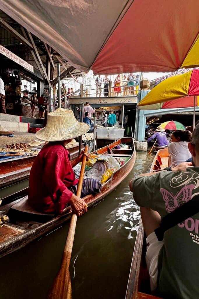 Damnoen Saduak’ta şemsiyelerin altında kanalda tekne turu: satıcı tekneleri ve pazar kalabalığı.