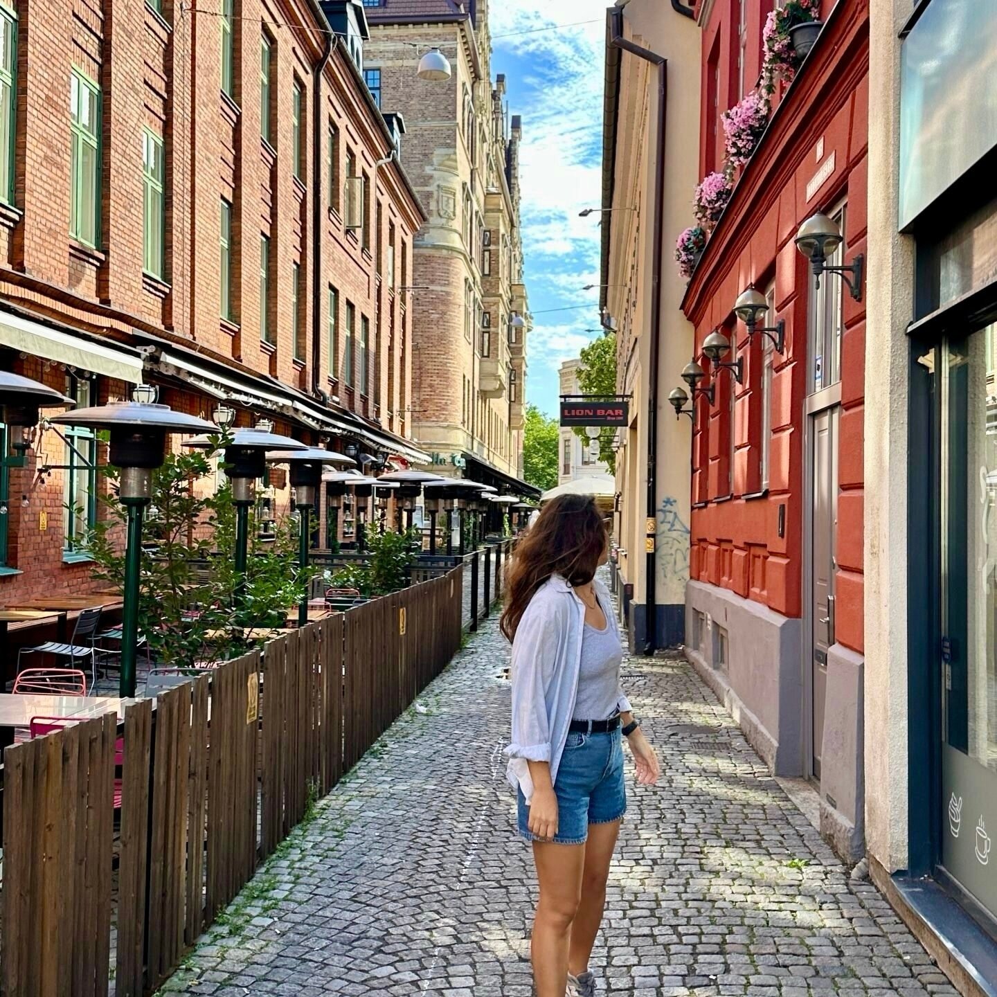 İsveç Malmö’de renkli tarihi binaların arasındaki dar taş sokak ve kafe terasları (gezi rehberi)