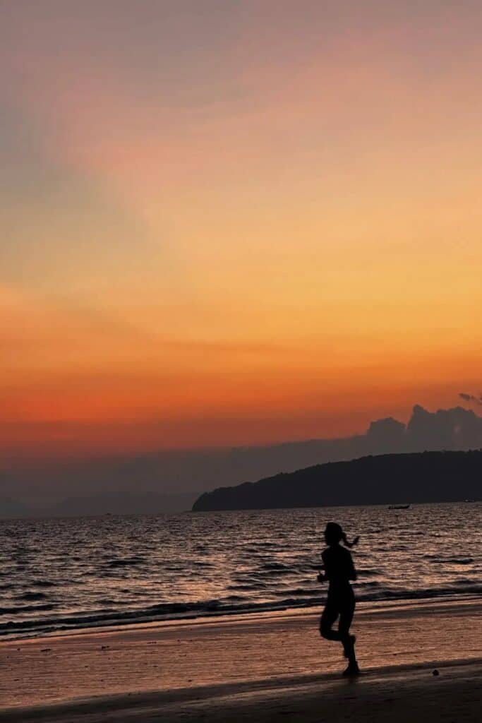 Krabi’de gün batımında sahilde koşan biri ve turuncu gökyüzü manzarası