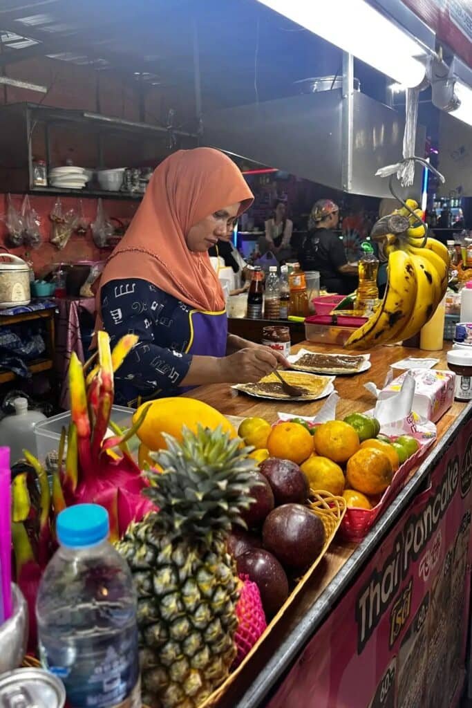 Krabi street food tezgahında tropikal meyveler ve sokak lezzetleri, Tayland gece pazarı