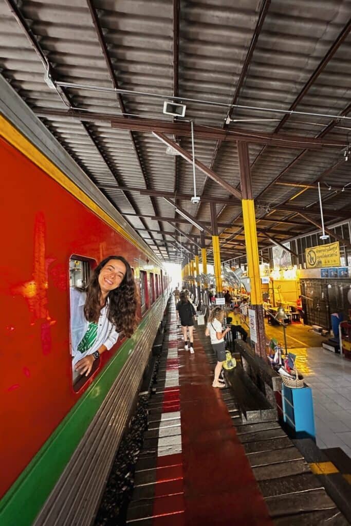 Maeklong Railway Market’te trenden kapıya uzanıp poz veren gezgin: tren pazarı deneyimi, Tayland.