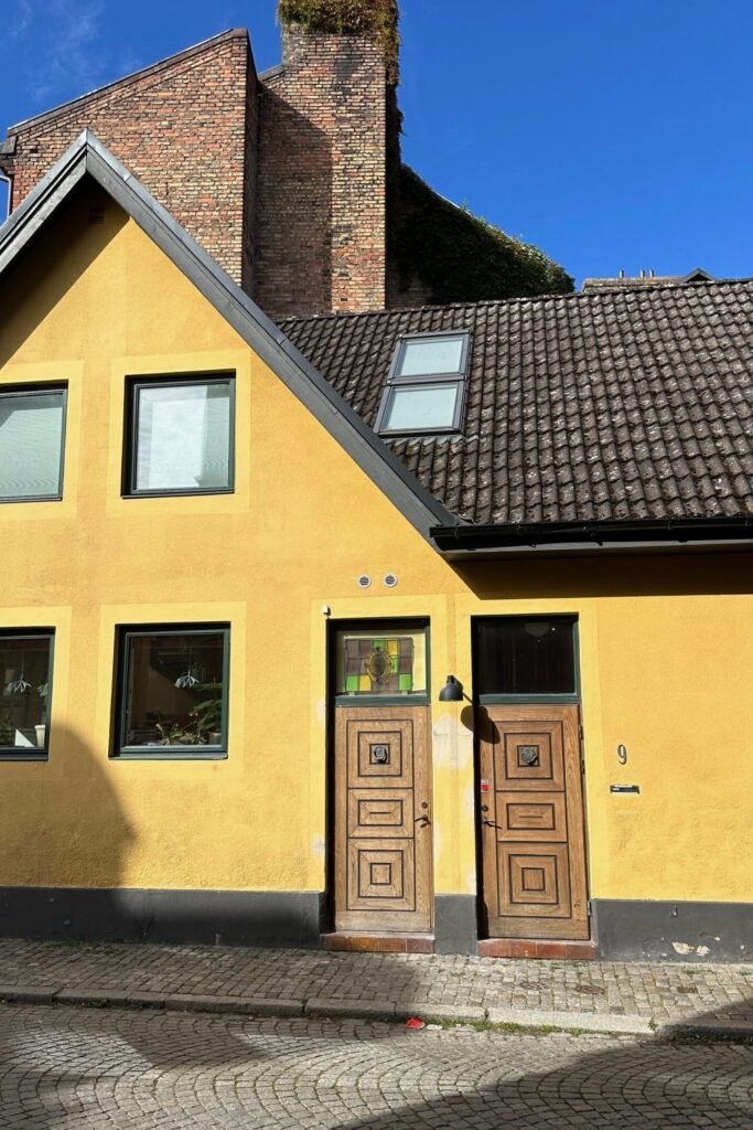 Malmö eski şehirde sarı cepheli geleneksel ev ve ahşap kapılar, Malmö gezi rehberi için fotojenik sokak detayı, İsveç
