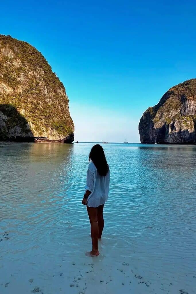 Phi Phi Maya Bay’de turkuaz denizde ayakta duran kişi ve arka planda kireçtaşı kayalıklar