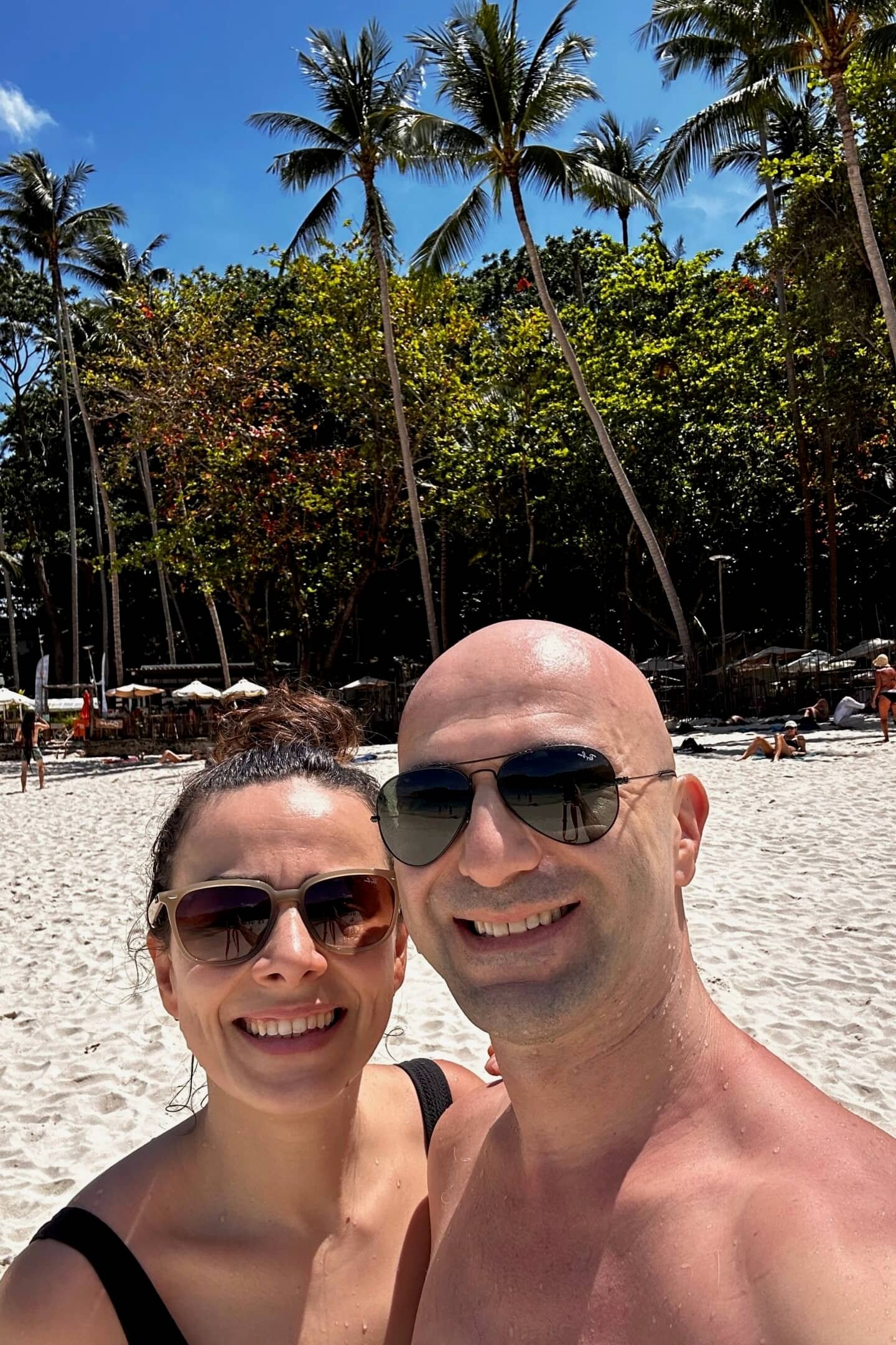 Phuket’te palmiye ağaçlı kumsalda güneşli günde çift