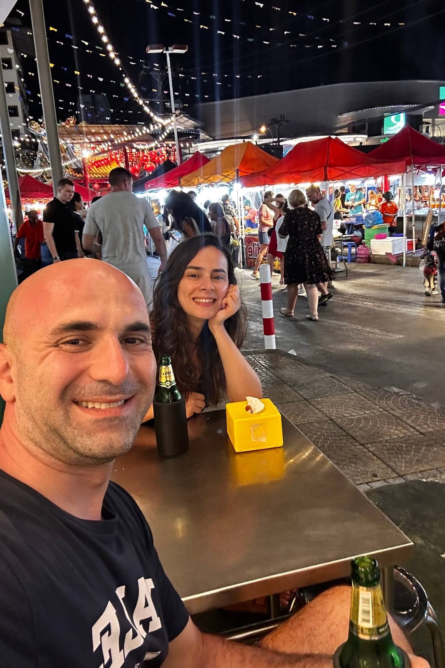 Phuket’te gece pazarında yeme içme alanı: tezgahlar ve ışıklar arasında oturan çift