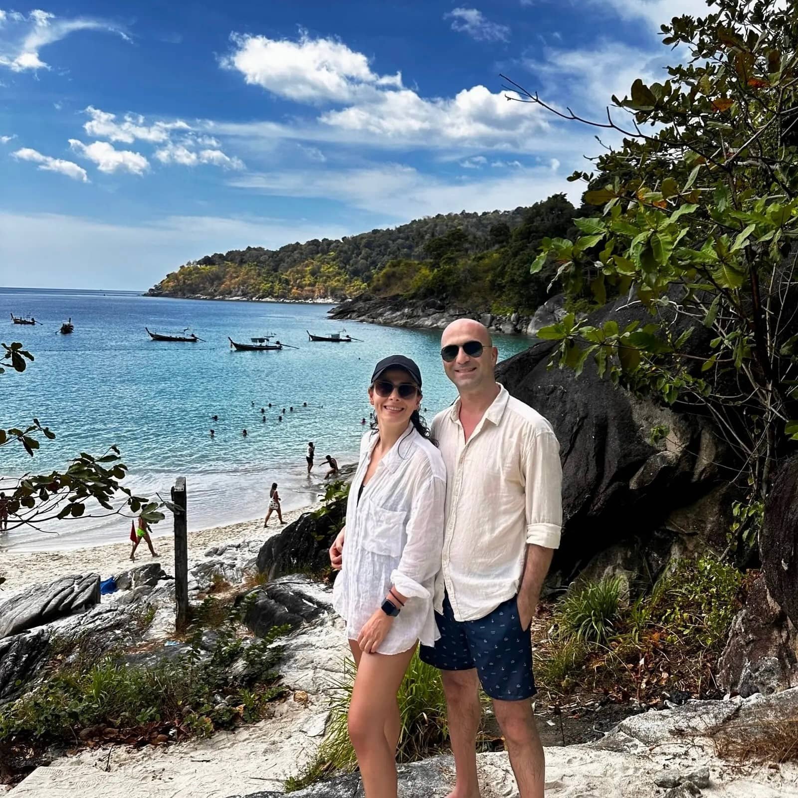 Phuket sahil manzarası turkuaz deniz, longtail tekneler ve kayalıklarda poz veren çift, Tayland