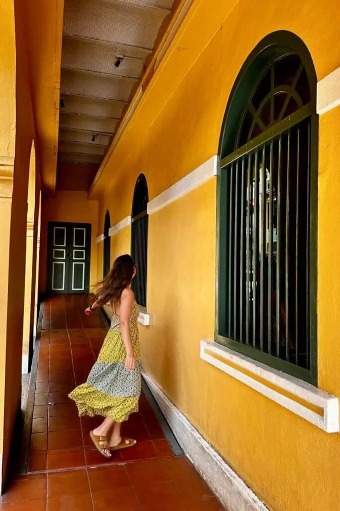 Phuket Old Town’da sarı renkli tarihi binanın kemerli koridorunda yürüyen kadın