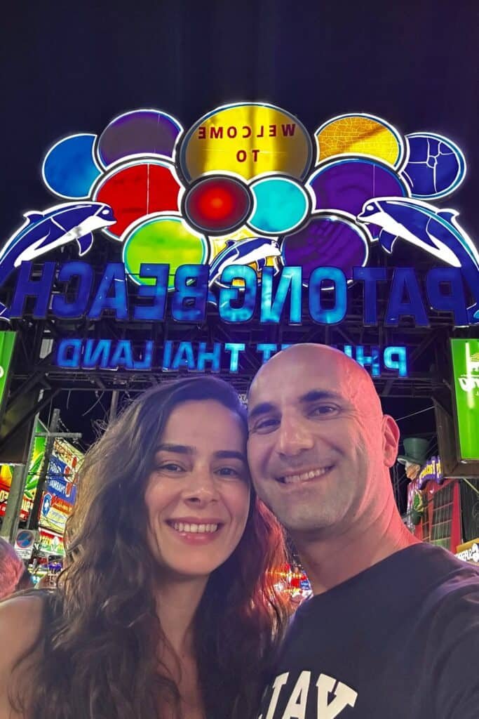 Phuket’te Patong Beach giriş tabelası önünde gece çekilmiş çift selfie