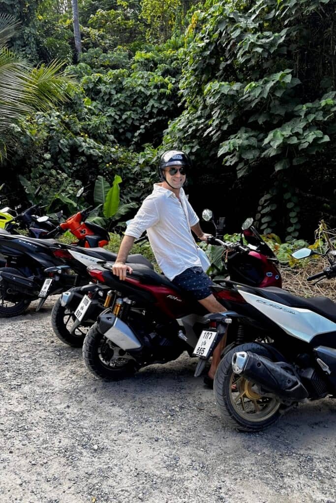 Phuket’te scooter kiralama için park alanında duran motorlar ve tropik orman manzarası