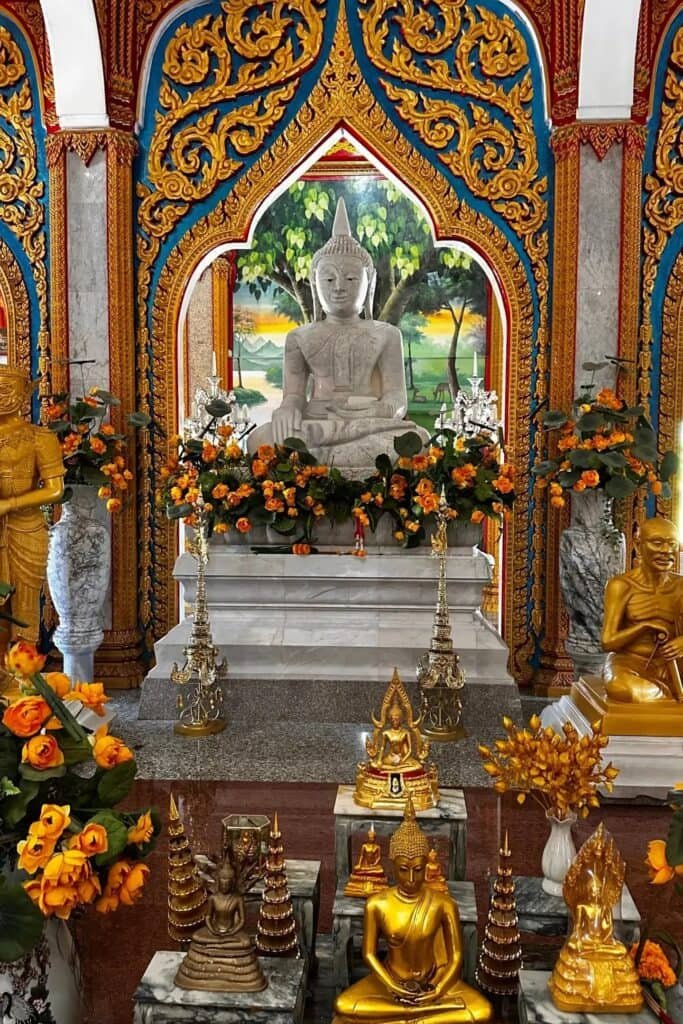 Phuket Wat Chalong Tapınağı içinde Buda heykelleri, çiçek süslemeleri ve altar detayı