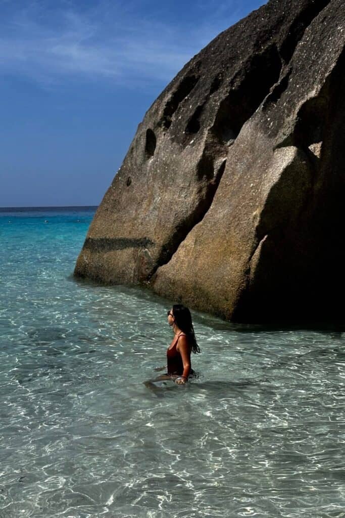 Similan Adaları’nda sığ, cam gibi denizde duran kadın ve dev granit kaya.