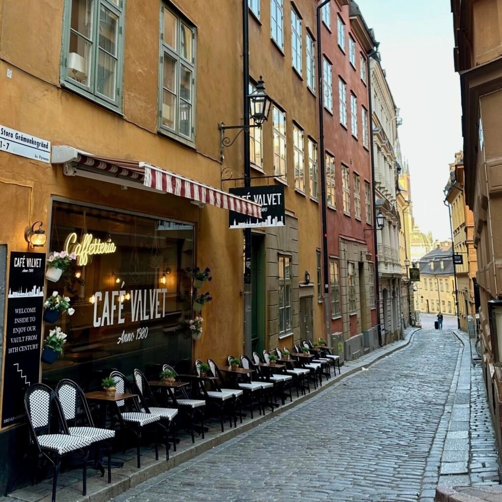 Stockholm Gamla Stan’daki Café Valvet’in önünde dar taş sokak manzarası ve dış mekan oturma alanı
