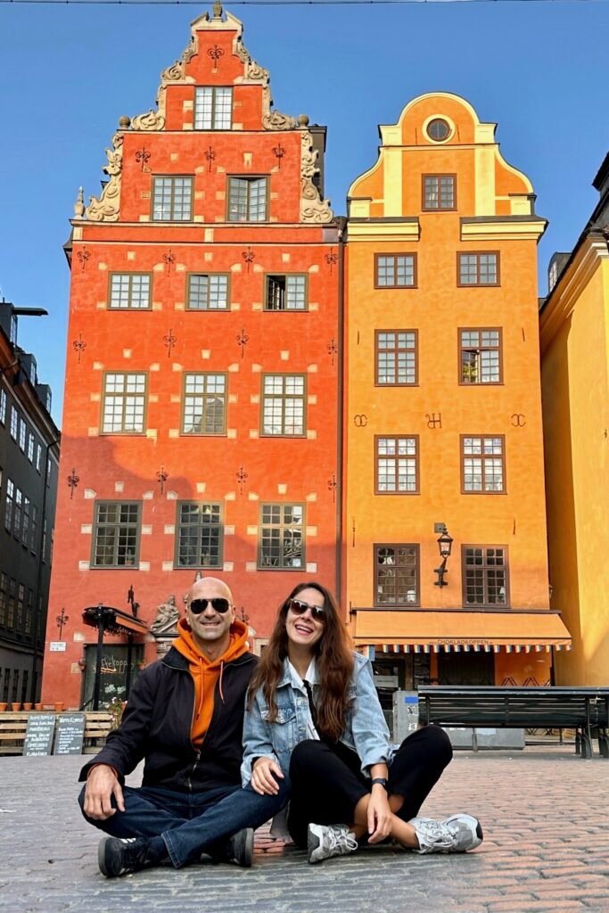 Stockholm Gamla Stan Stortorget Meydanı’nda renkli tarihi evler önünde oturan çift fotoğrafı