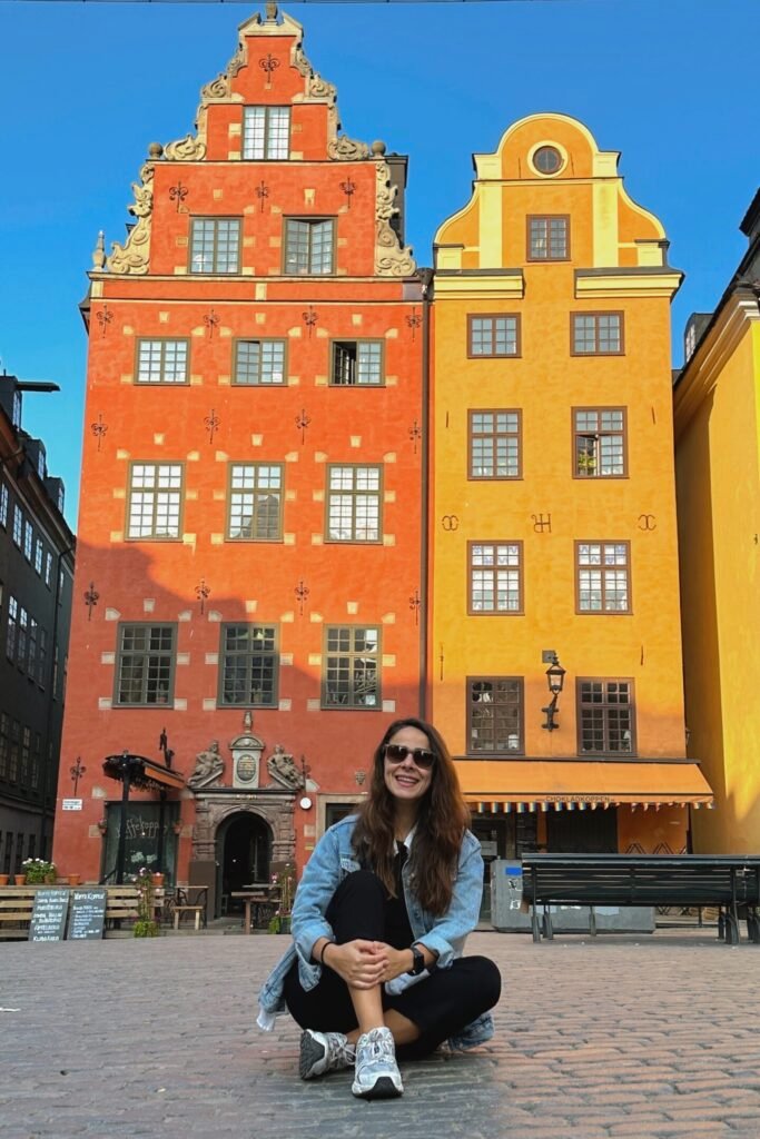 Gamla Stan Stortorget meydanında renkli tarihi binalar önünde oturan kadın, Stockholm gezi rehberi görseli