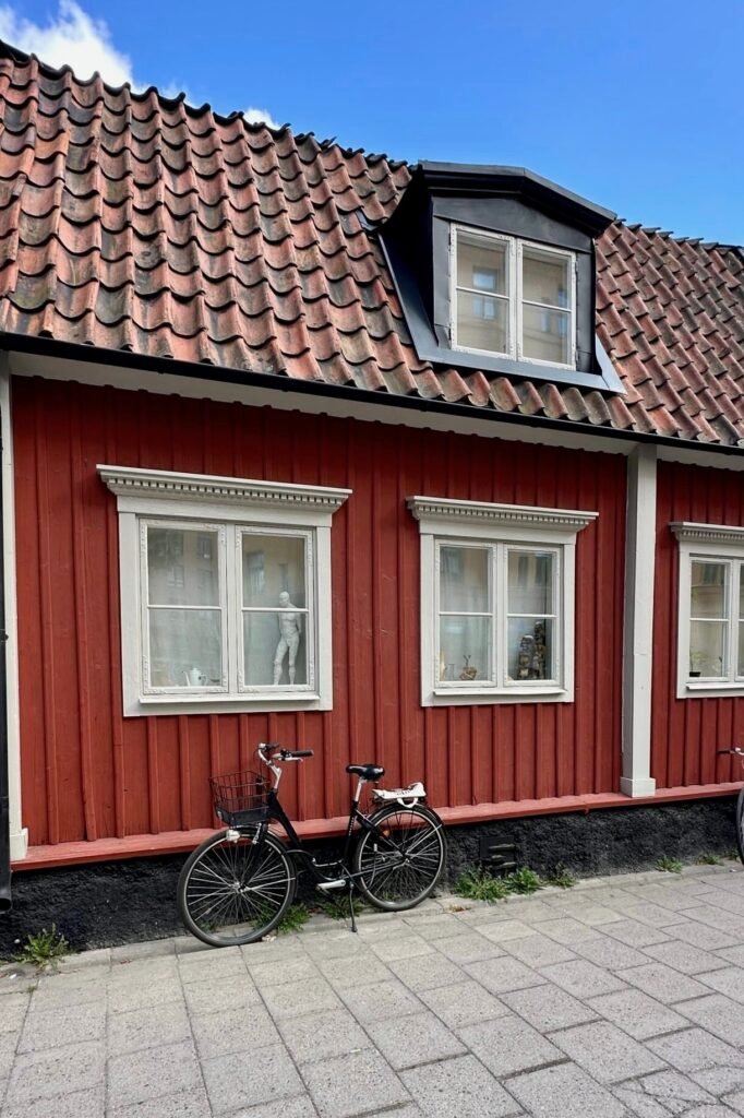 Stockholm Södermalm’de kırmızı ahşap İsveç evi önünde park edilmiş bisiklet, yerel sokak detayı