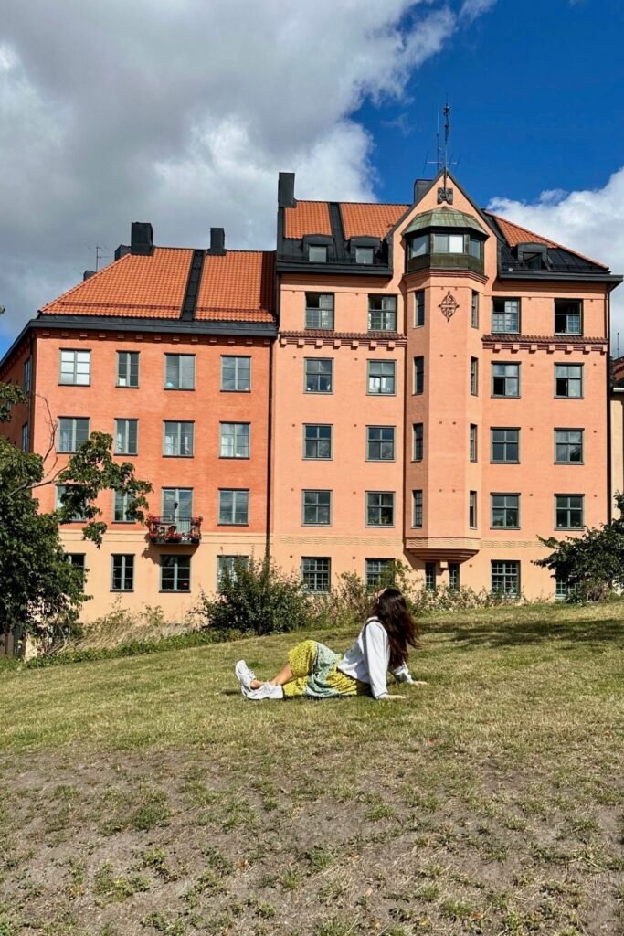 Stockholm Södermalm’de parkta çimlerin üzerinde dinlenirken arka planda tarihi apartman manzarası