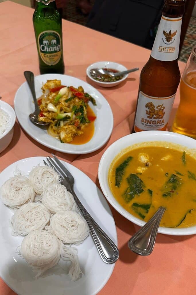 Tayland akşam yemeği: köri, pirinç eriştesi ve Singha–Chang biralarıyla masa düzeni