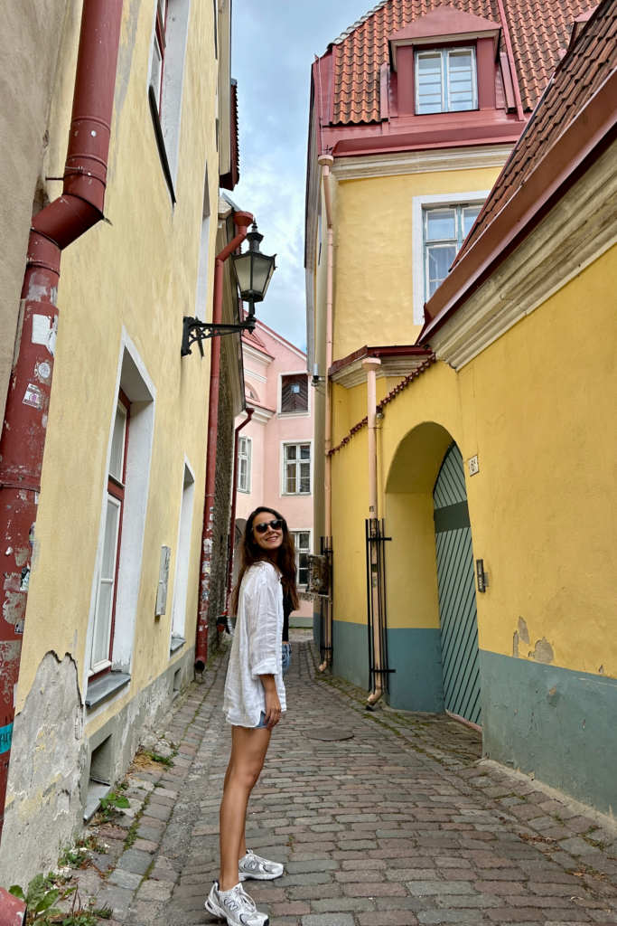 Tallinn Eski Sehir’de dar bir sokakta sari ve pastel renkli tarihi binalar arasinda cekilen gezi fotografi.