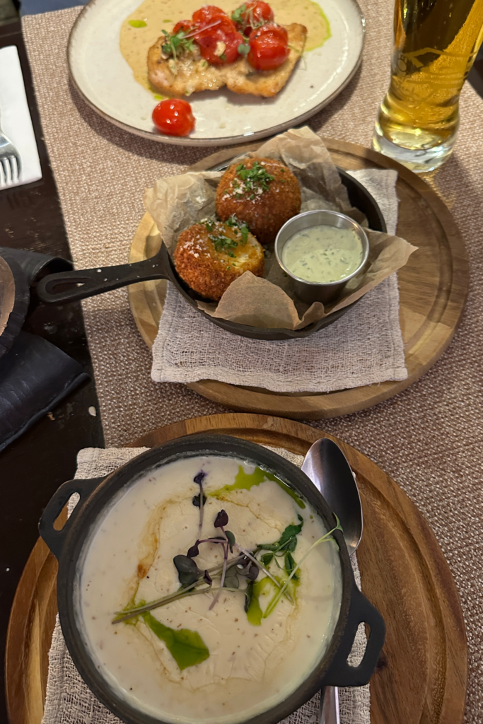 Tallinn’de restoranda siparis edilen yemekler: kremali corba, kroket ve bira ile masa gorunumu.