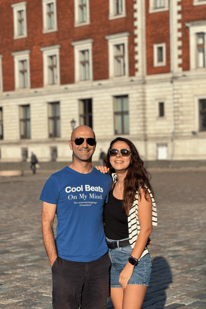 Riga Old Town’da taş meydanda tarihi bina önünde poz veren çift